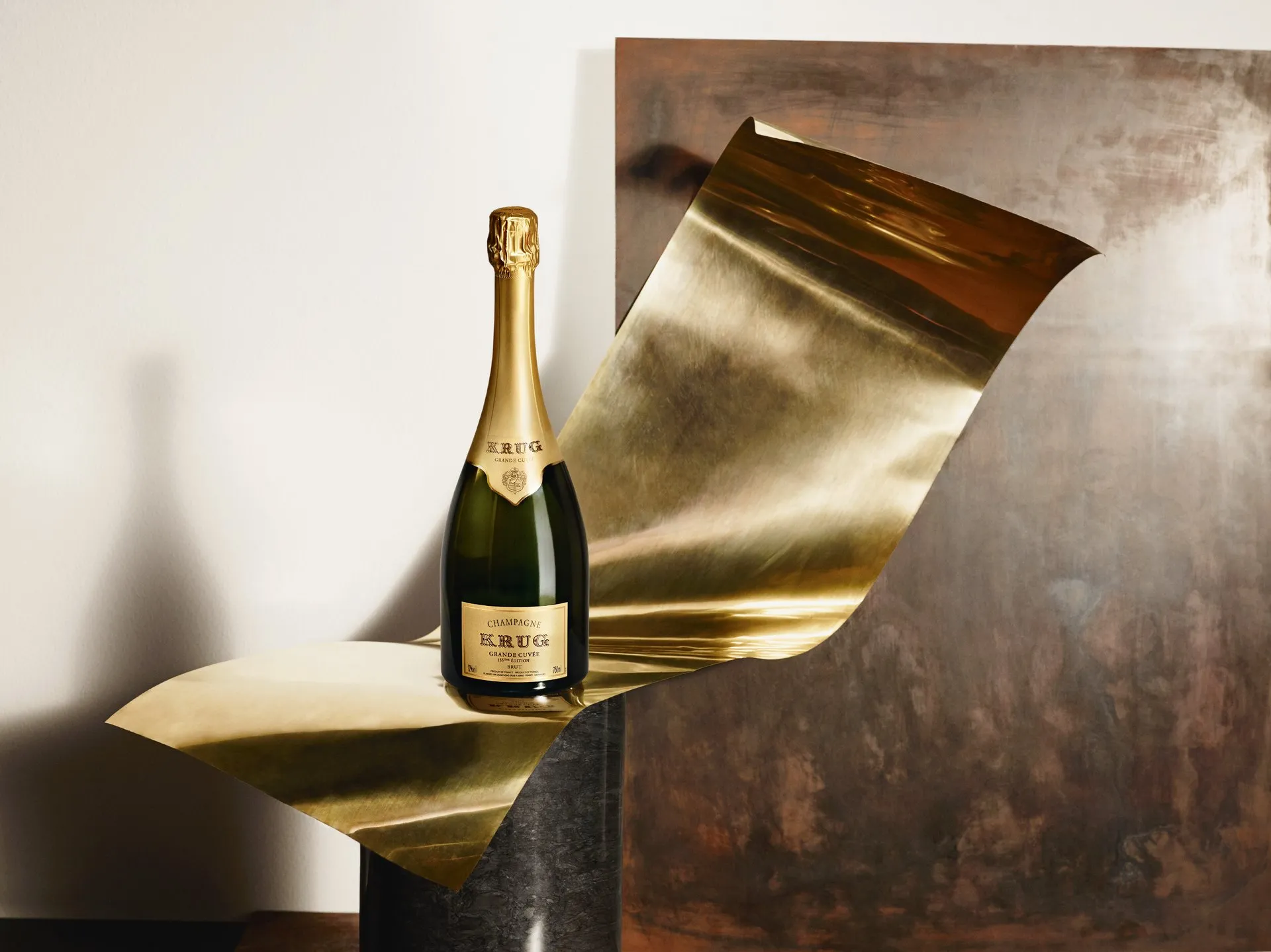Garrafa de Krug Grande Cuvée sobre uma folha de metal dourado